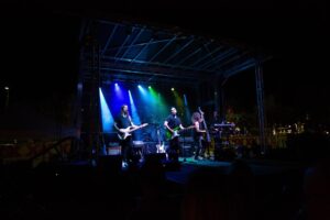 Band performing under blue and green stage lighting on the APEX 2016 mobile stage at night