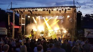 Band performing in haze and yellow spotlights on the APEX 2420 mobile stage as a seated crowd watches