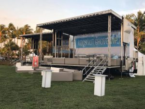 APEX 3224 GEN5 mobile stage set up as a VIP lounge on a lawn, with sofas and low tables in front of the deck