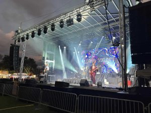 Band performing on the APEX 3224 GEN5 mobile stage at a fairground at dusk, with an LED wall behind them