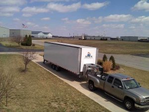 Apex Stages mobile stage packed into its towable trailer and hitched to a pickup truck outside the Apex Stages facility