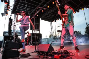 Singer and bass player performing under red stage lighting on the APEX 3224 GEN5 mobile stage