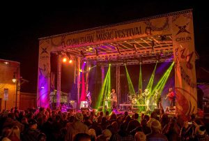 APEX 3224 GEN5 mobile stage dressed in printed festival scrims and lit in green and pink above a night crowd